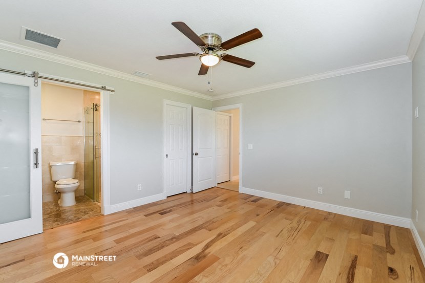 a renovated living room with wood floors and a ceiling fan