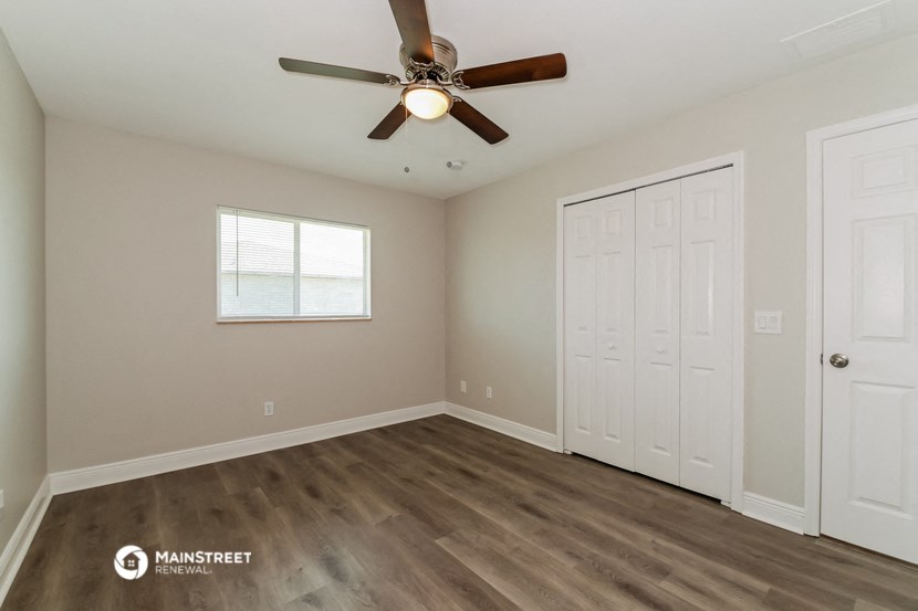 the spacious living room with a ceiling fan and a closet