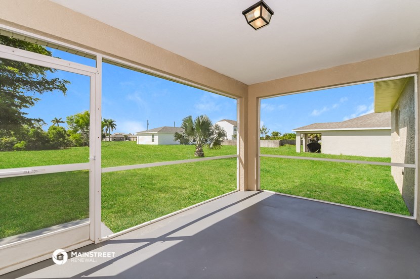 the view from the screened in porch of a home with large windows