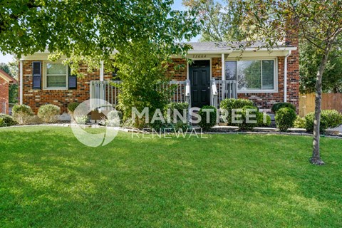 a small brick house with a lawn and trees in front of it