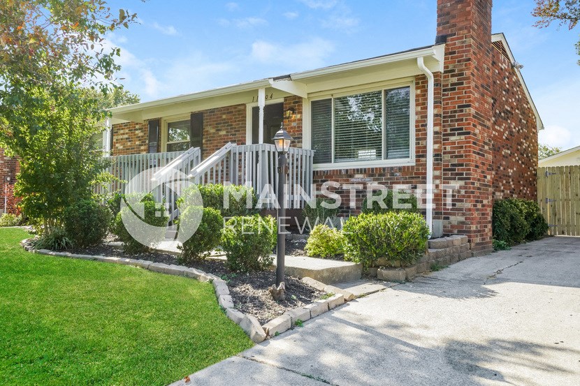 a small brick house with a front porch and a sidewalk