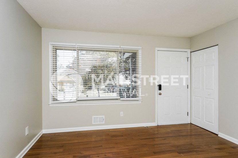 an empty living room with wood floors and a large window