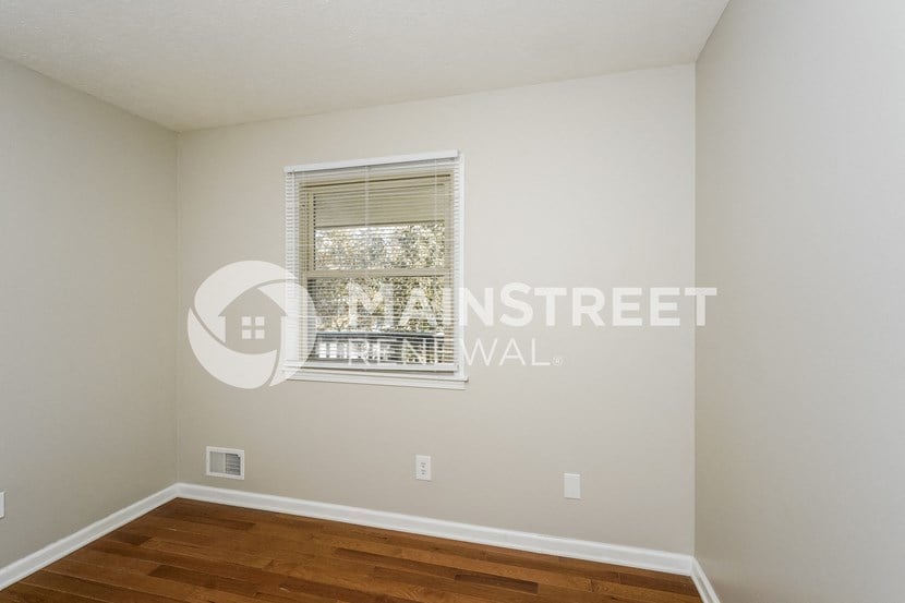 a bedroom with a wood floor and a window