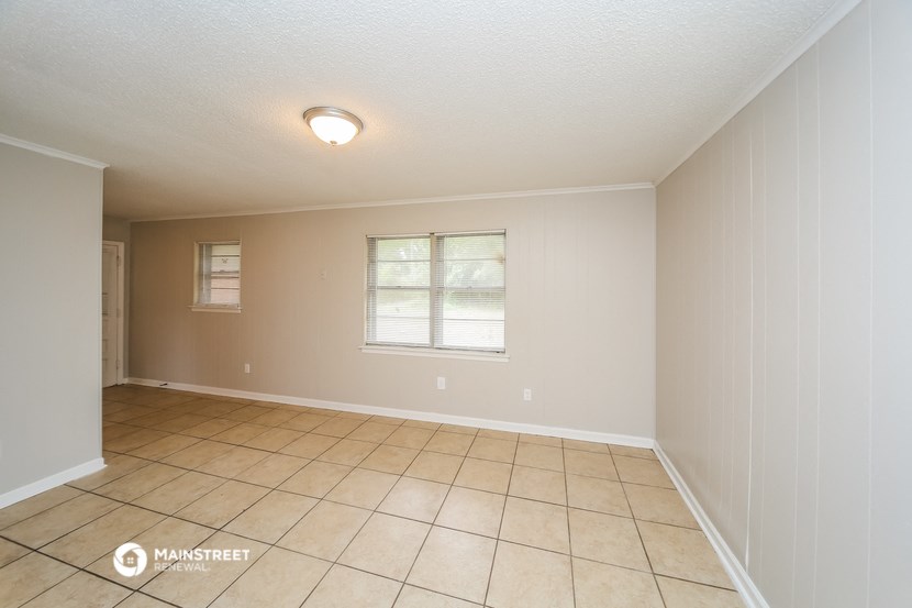 an empty living room with tile flooring and a window