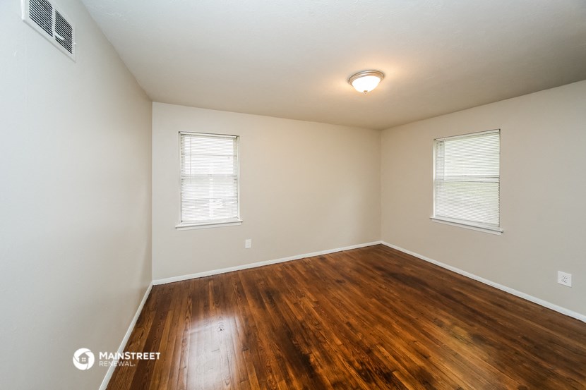 the spacious living room with hardwood flooring and two windows