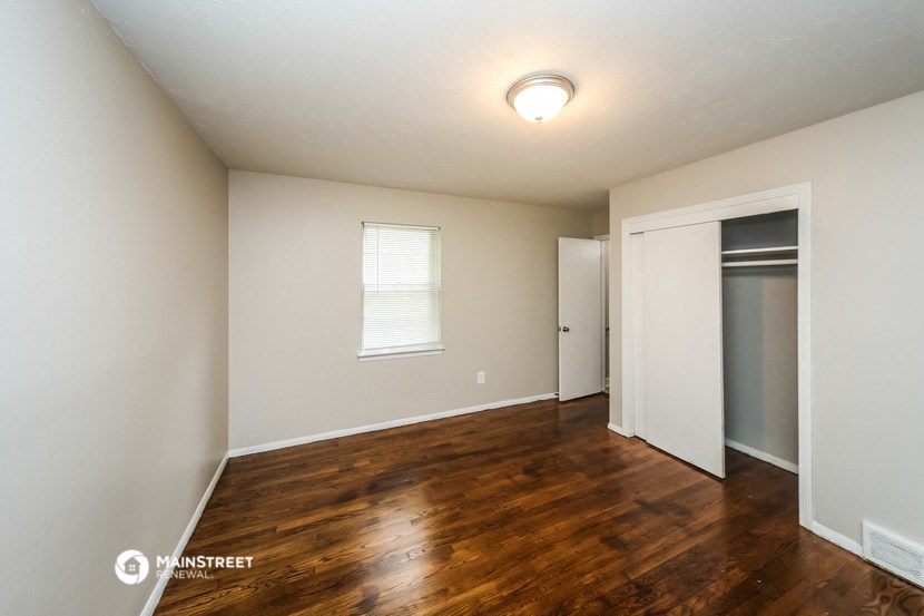 the interior of an empty living room with wood flooring and a closet