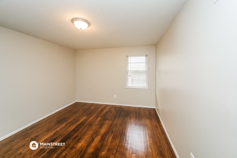 the spacious living room with hardwood flooring and a window