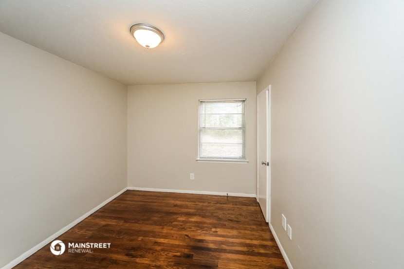 the spacious living room with hardwood flooring and a window