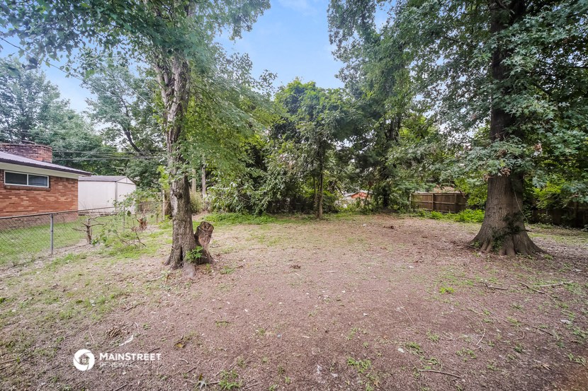 a yard with two trees and a house in the background