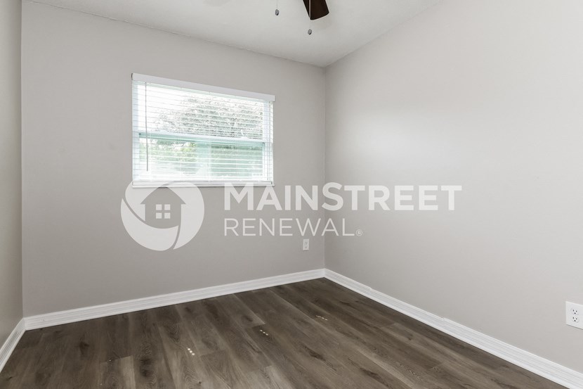 a bedroom with hardwood flooring and a window
