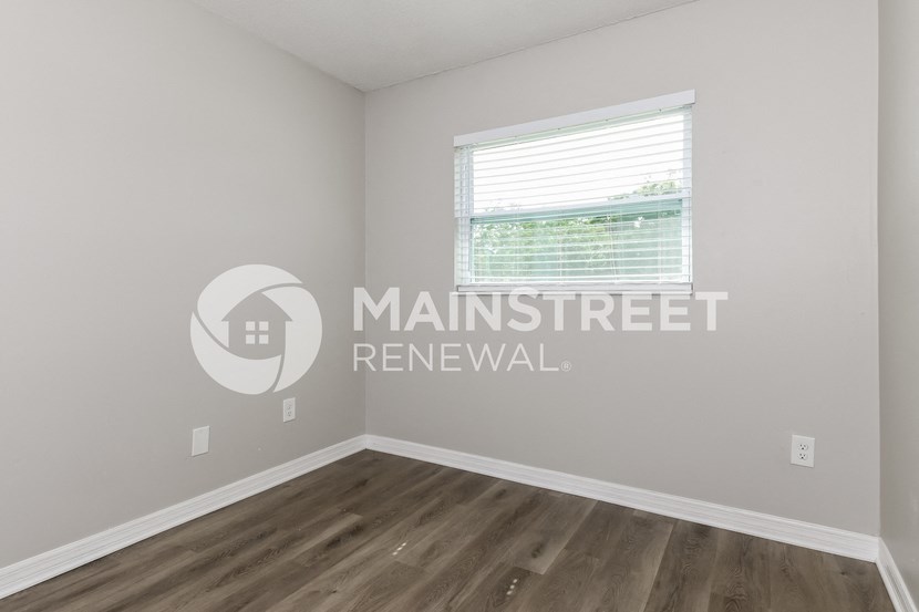 a bedroom with hardwood flooring and a window