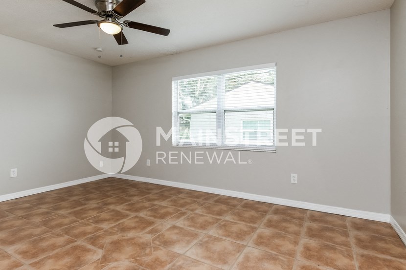 an empty living room with a window and a ceiling fan