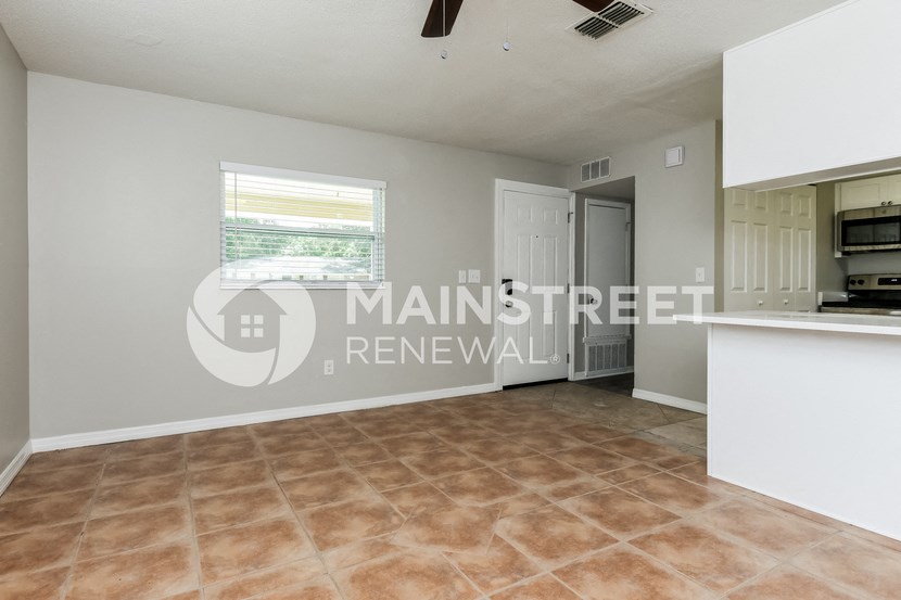 a large living room with a kitchen and a large window