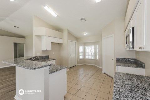a kitchen with granite counter tops and white cabinets and a hallway with a door
