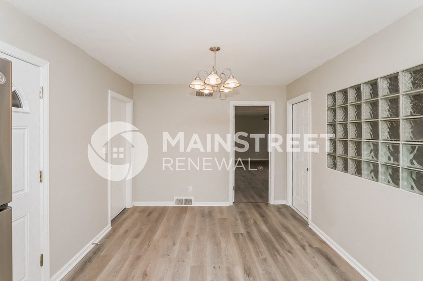 a renovated hallway with white walls and white doors and a chandelier