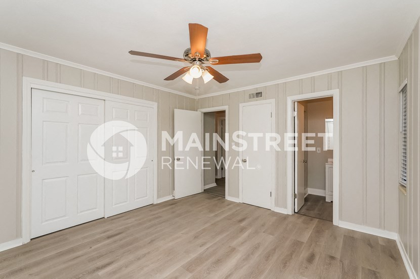 a living room with white walls and a ceiling fan