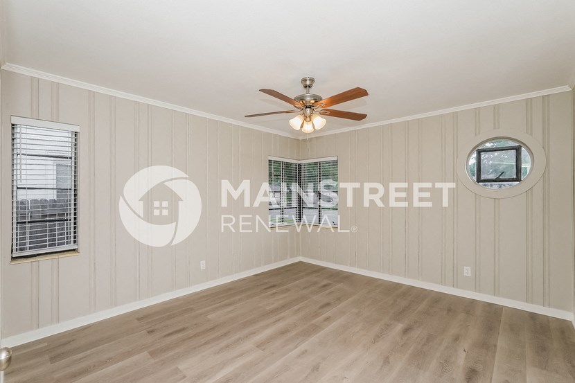 a spacious living room with wood floors and a ceiling fan