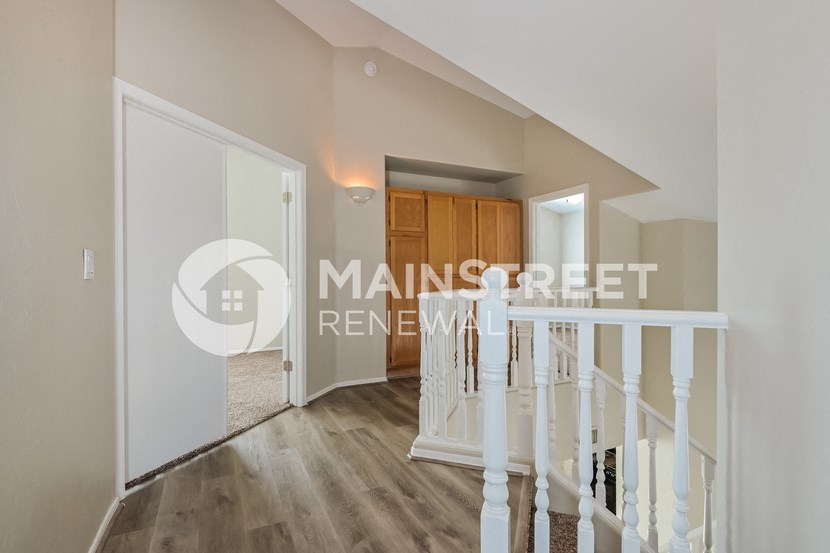 a bedroom upstairs with a staircase and a door to a hallway
