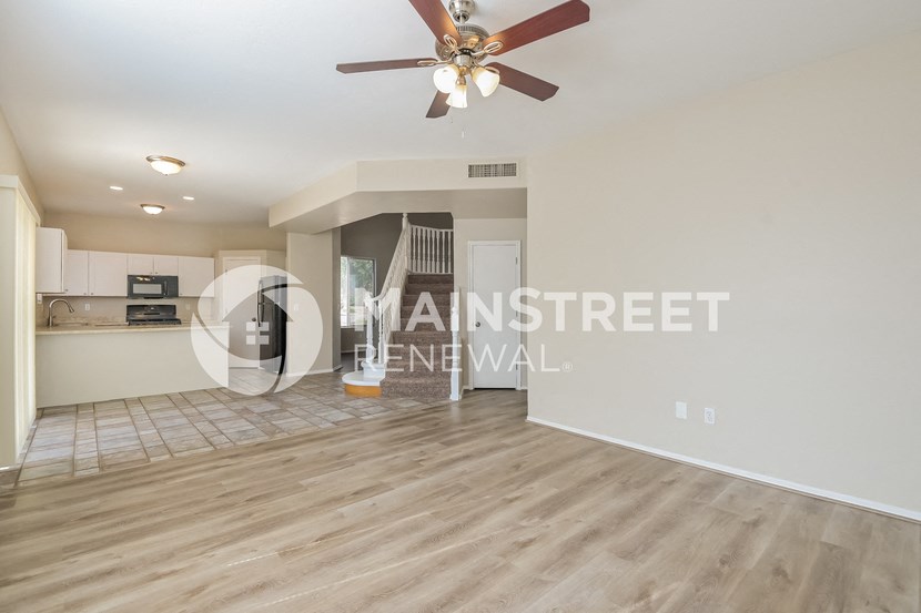 a renovated living room with a kitchen and a ceiling fan