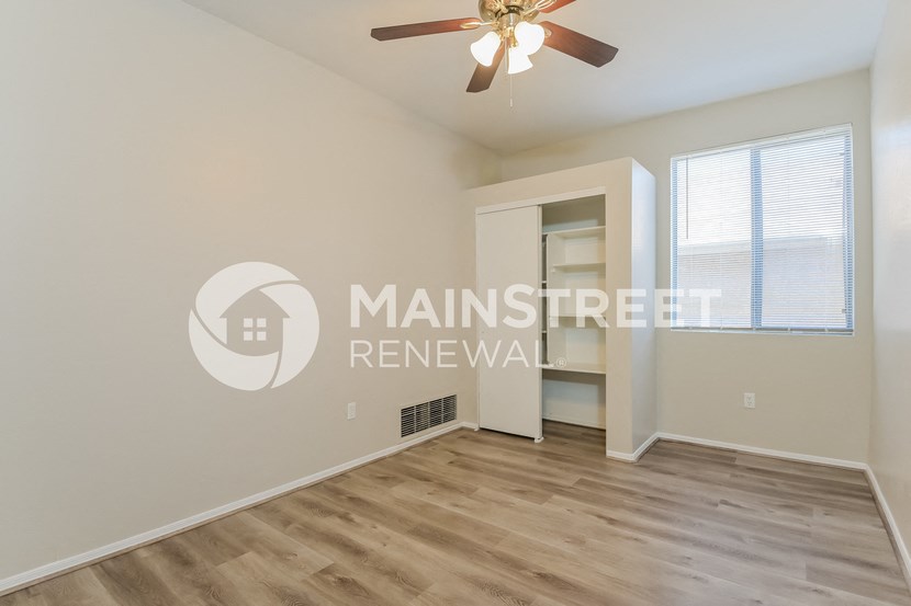 a large living room with a ceiling fan and a closet