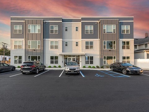 an apartment building with cars parked in a parking lot