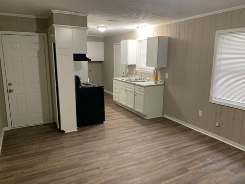 A kitchen with white cabinets and a black refrigerator.