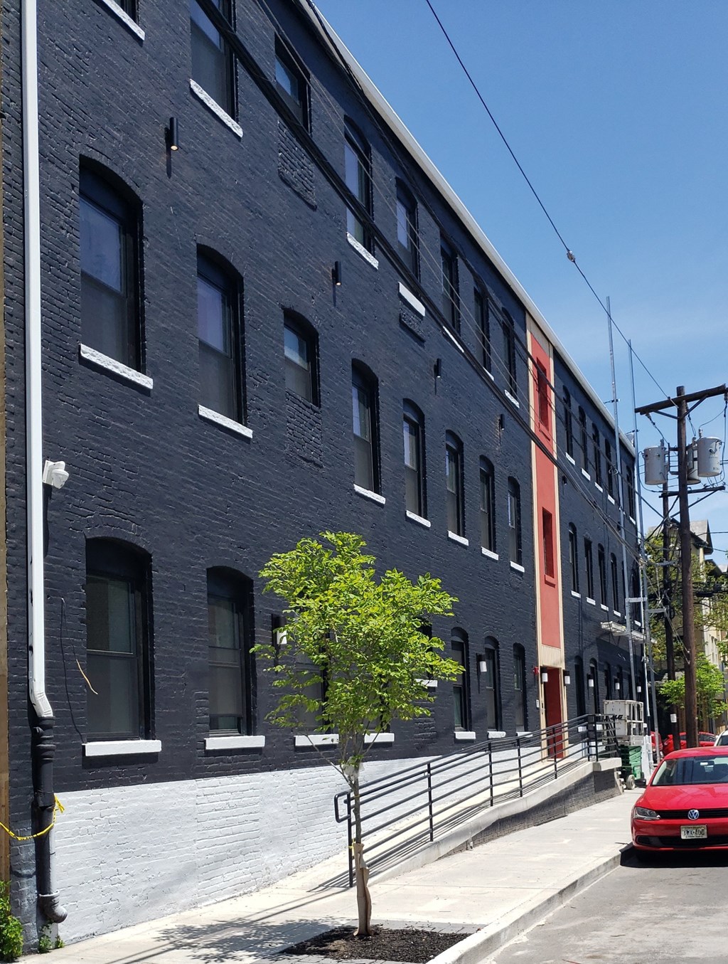 a black brick building with a red car on a street