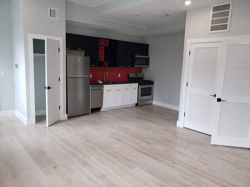 a renovated kitchen with white cabinets and a stainless steel refrigerator