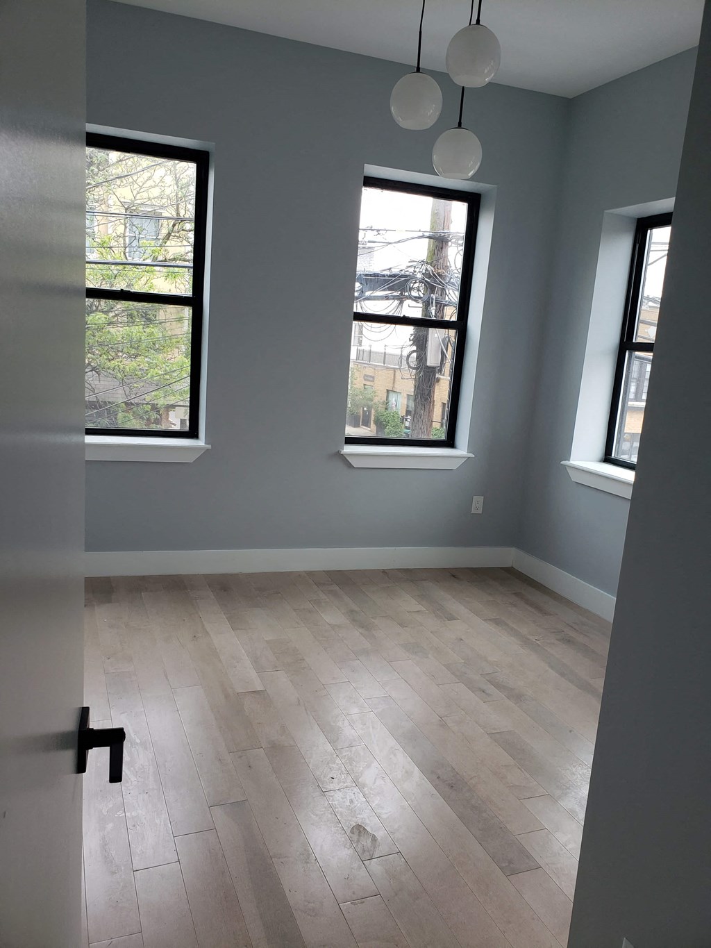 a room with a hard wood floor and three windows