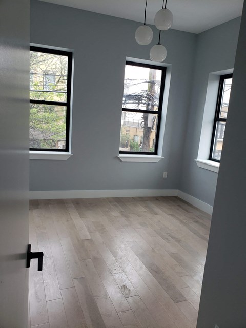 a room with a hard wood floor and three windows