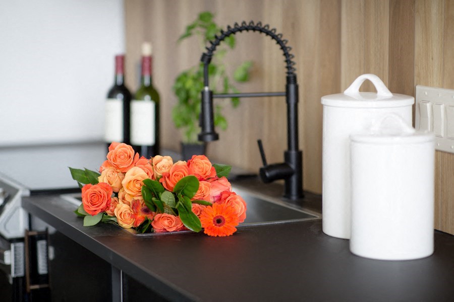 A bunch of orange roses are on a black countertop.