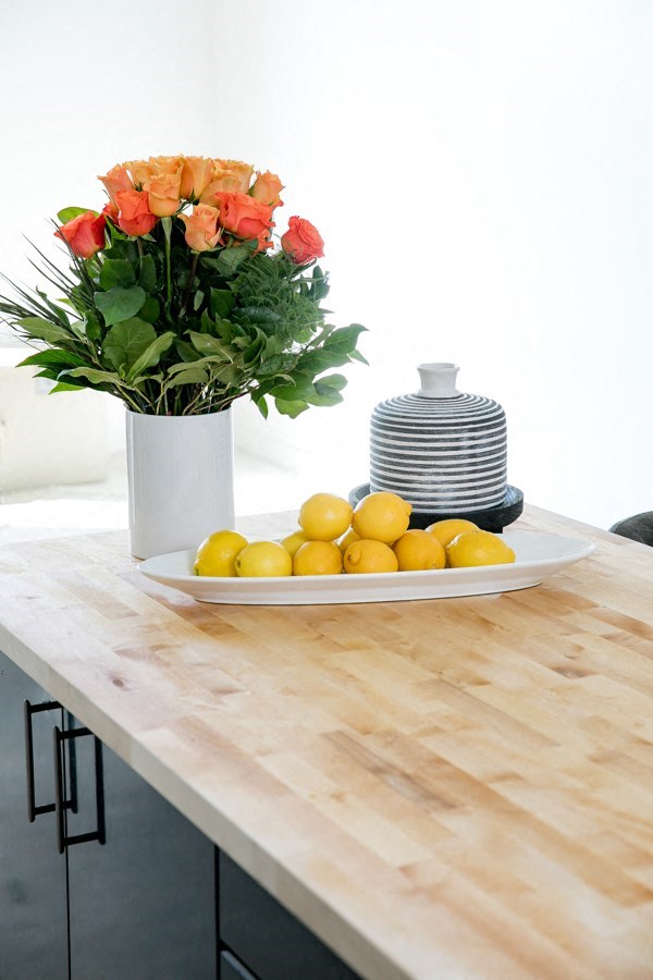 A vase of flowers sits on a table with lemons.