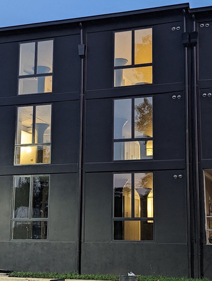 A black building with windows reflecting the sky.