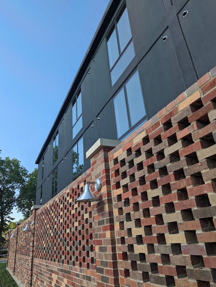 A brick wall with a black building in the background.