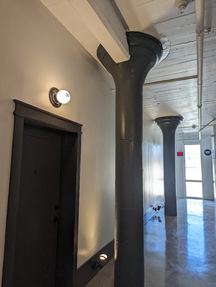 A hallway with a door and a light on the wall.