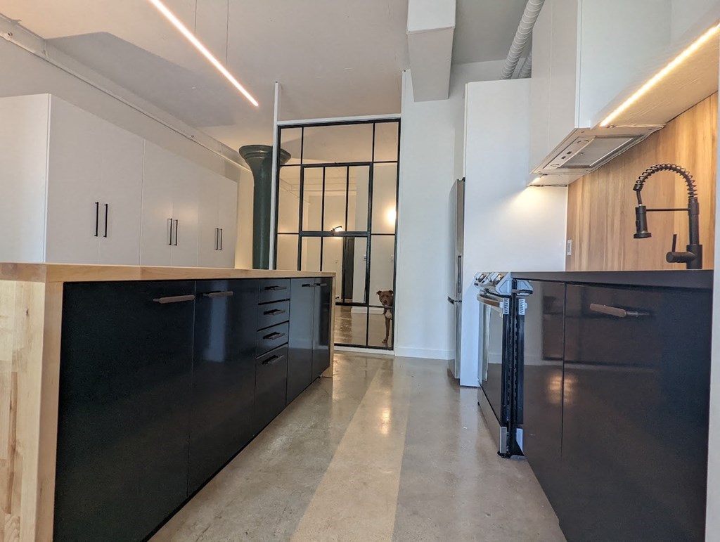A kitchen with black cabinets and a white counter.