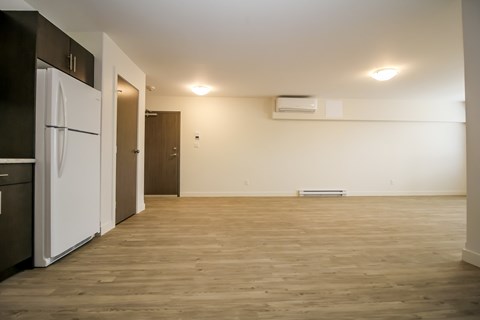 A kitchen with a white fridge and wooden floors.