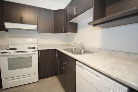 A kitchen with a white stove top oven and a white dishwasher.