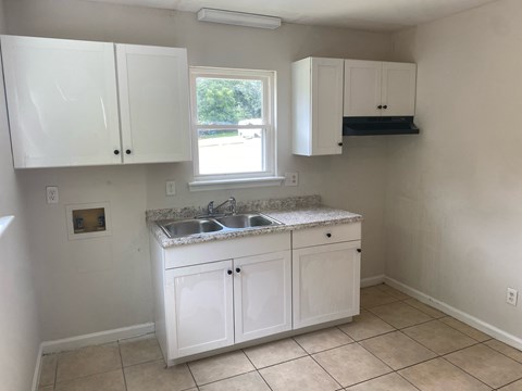an empty kitchen with white cabinets and a sink