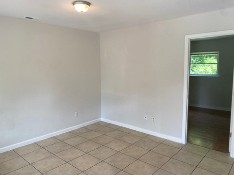 an empty living room with a tiled floor and a window