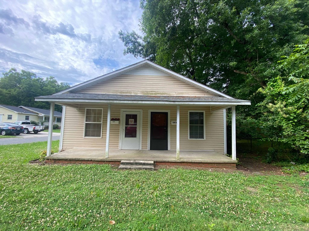 a small white house with a porch and a lawn