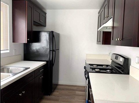 A kitchen with a black fridge and stove top oven.