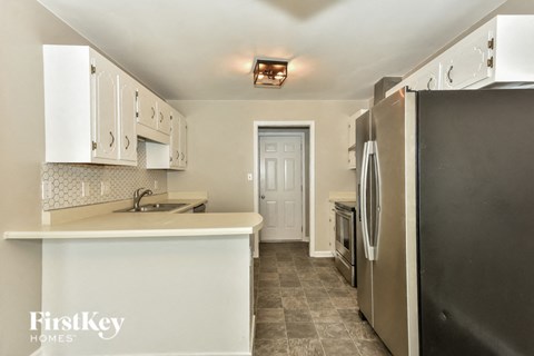 A kitchen with a refrigerator on the right and a sink in the middle.