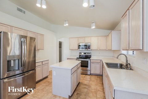 A kitchen with a refrigerator, sink, and stove.