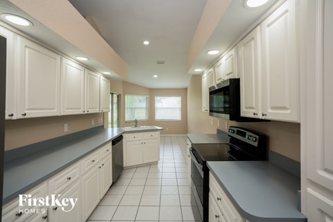 A kitchen with white cabinets and black appliances.