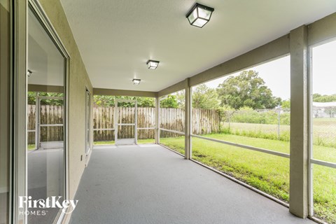 A long hallway with a view of a fence and trees outside.