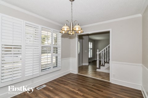 a dining room with white plantation shutters and a chandelier