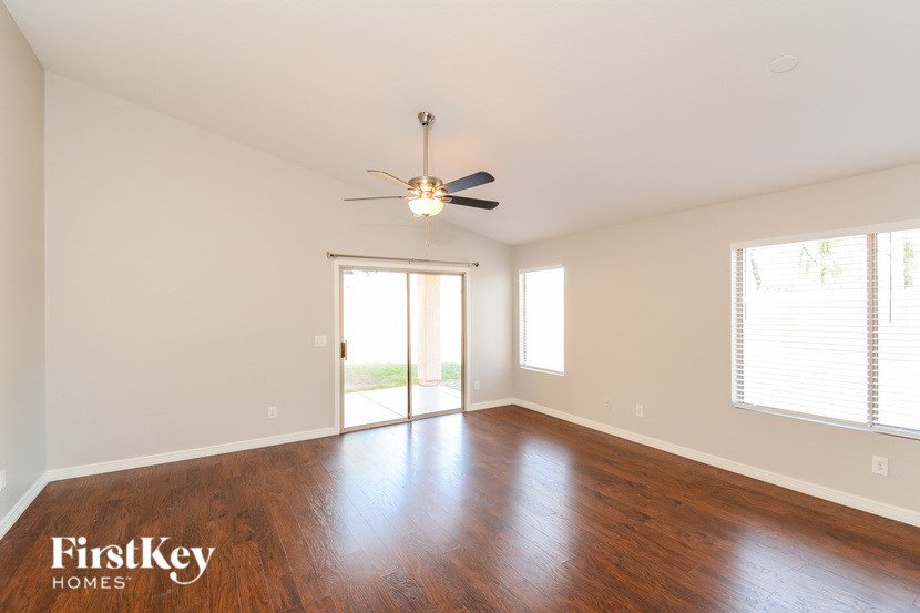 A spacious room with a ceiling fan and sliding glass doors leading to a balcony.