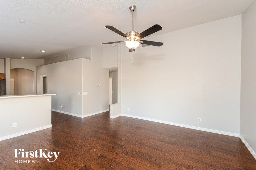 A spacious room with a ceiling fan and wooden flooring.