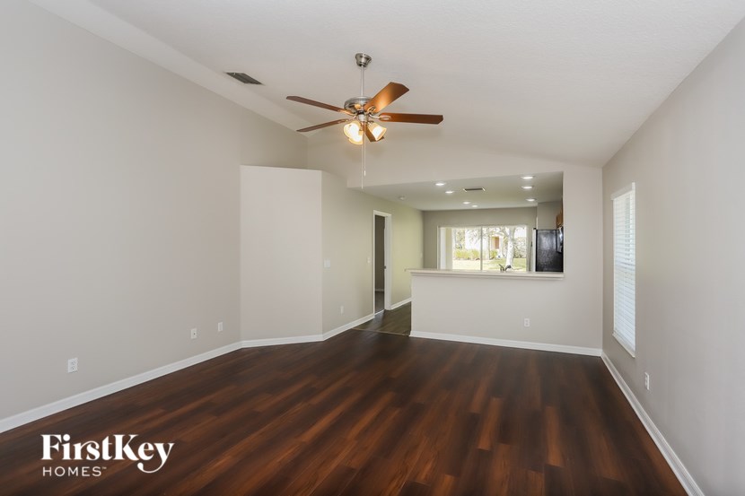 A spacious room with a ceiling fan and wooden flooring.